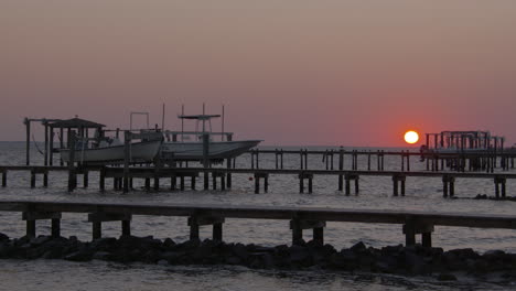 sun setting at a dock on the coast