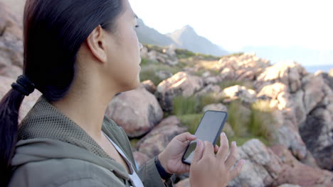 hiking in mountains, woman using smartphone to navigate rocky terrain