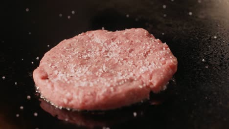 un primer plano de una chuleta de carne cruda para una hamburguesa frita en una parrilla eléctrica comercial.