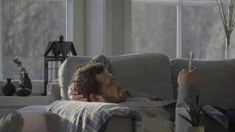 caucasian business man relaxed on couch scrolling through his mobile