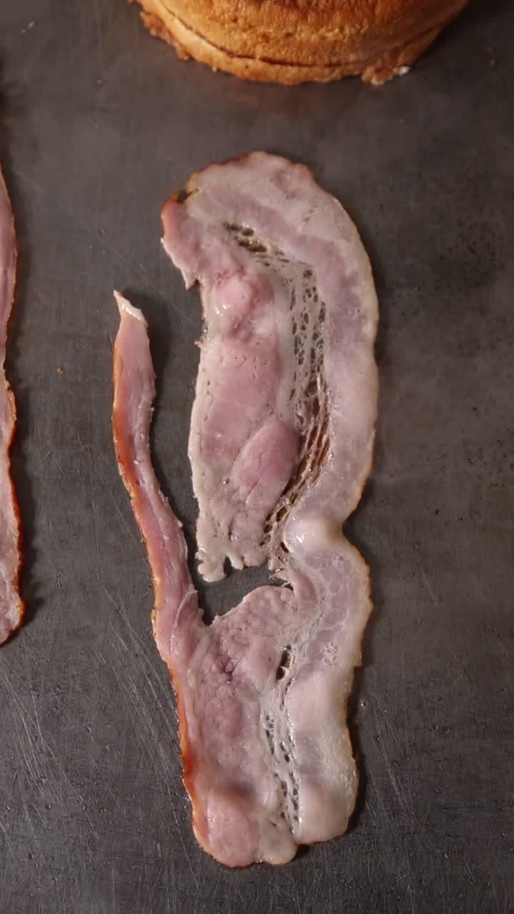 Primo piano di bacon che frigge su una piastra calda