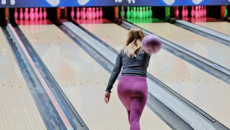 focused woman rolls violet ball neon bowling alley leaving just one pin standing