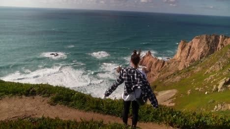 woman hiking on cliffside overlooking the ocean