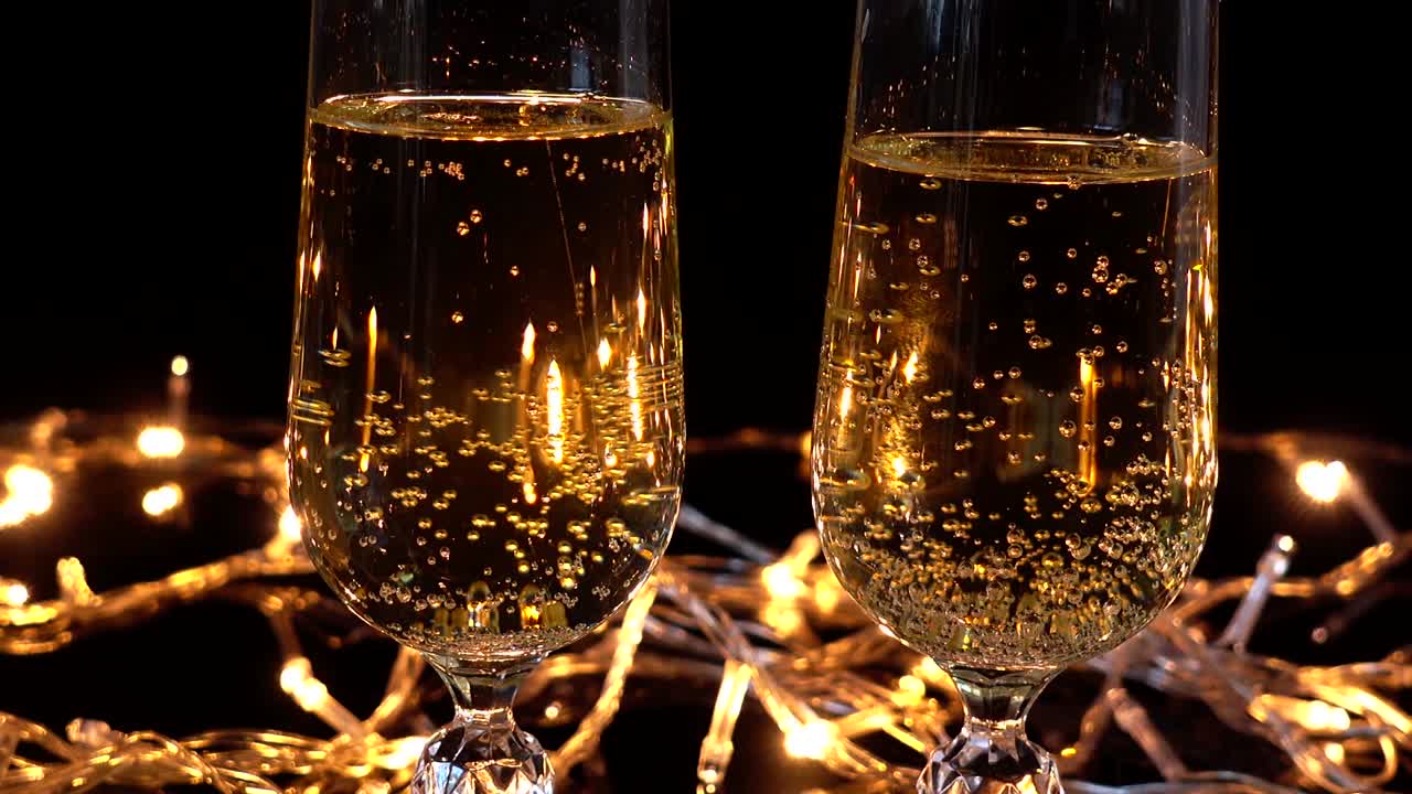 Calici da champagne e una rosa sullo sfondo di ghirlande luminose