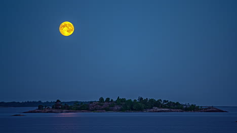 La-Puesta-De-Luna-Llena-Sobre-Un-Islote-En-Un-Mar-En-Calma---Lapso-De-Tiempo-Nocturno