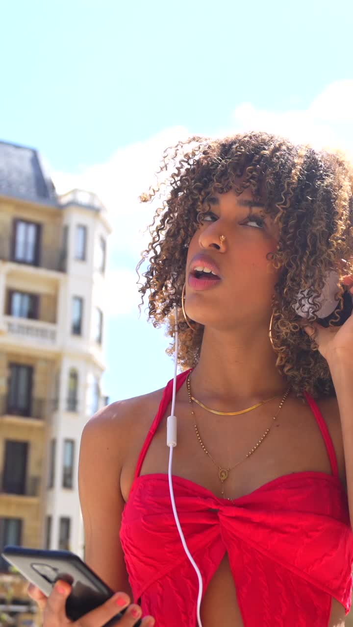 Woman with curly hair listening to music outdoors