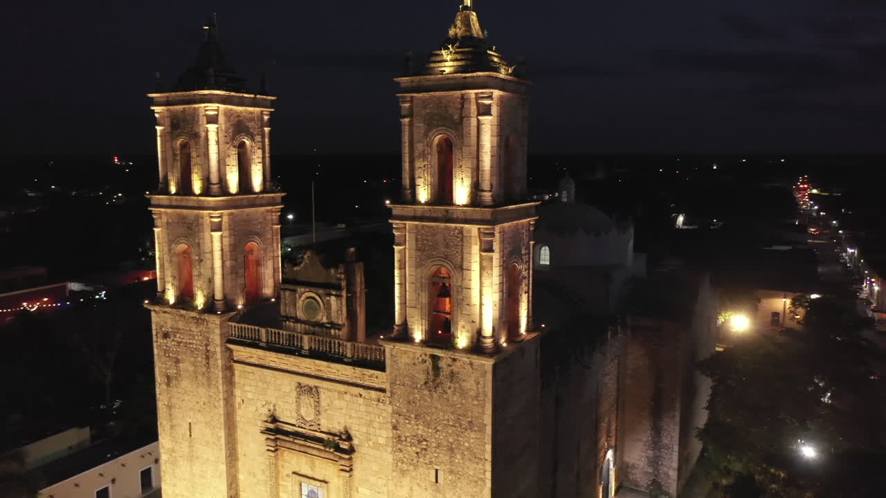 Aerial closeup nighttime orbit around the front of the Cathedral de San Gervasio in Valladolid, Yucatan, Mexico