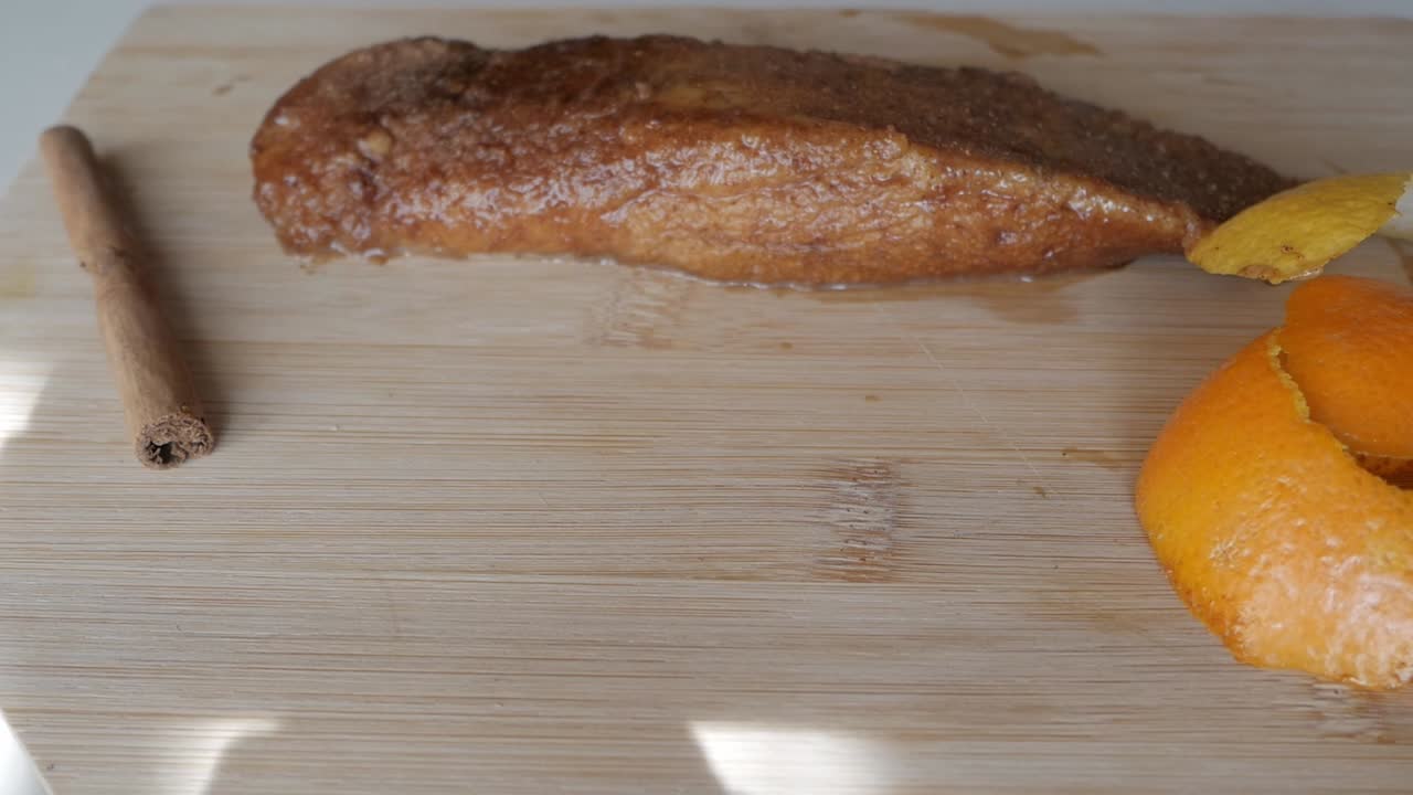 Freshly made Torrijas with cinnamon stick and orange peel on a wooden cutting board