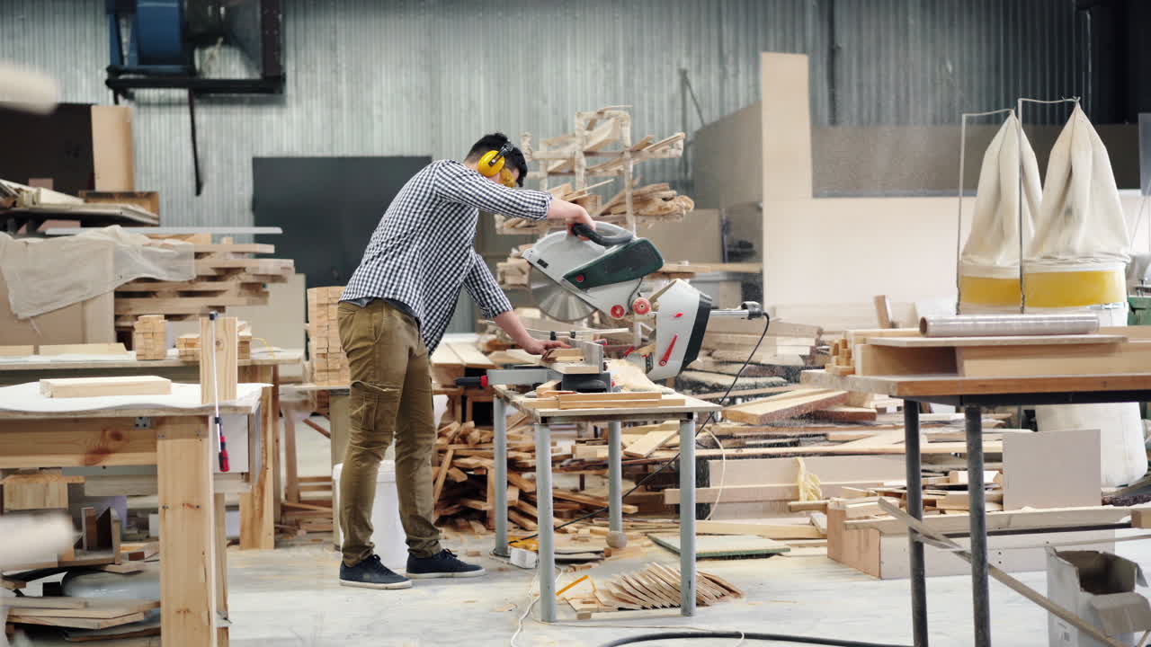 Man using a chop saw in a woodworking workshop