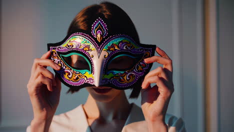 a woman holding a masquerade mask in front of her face