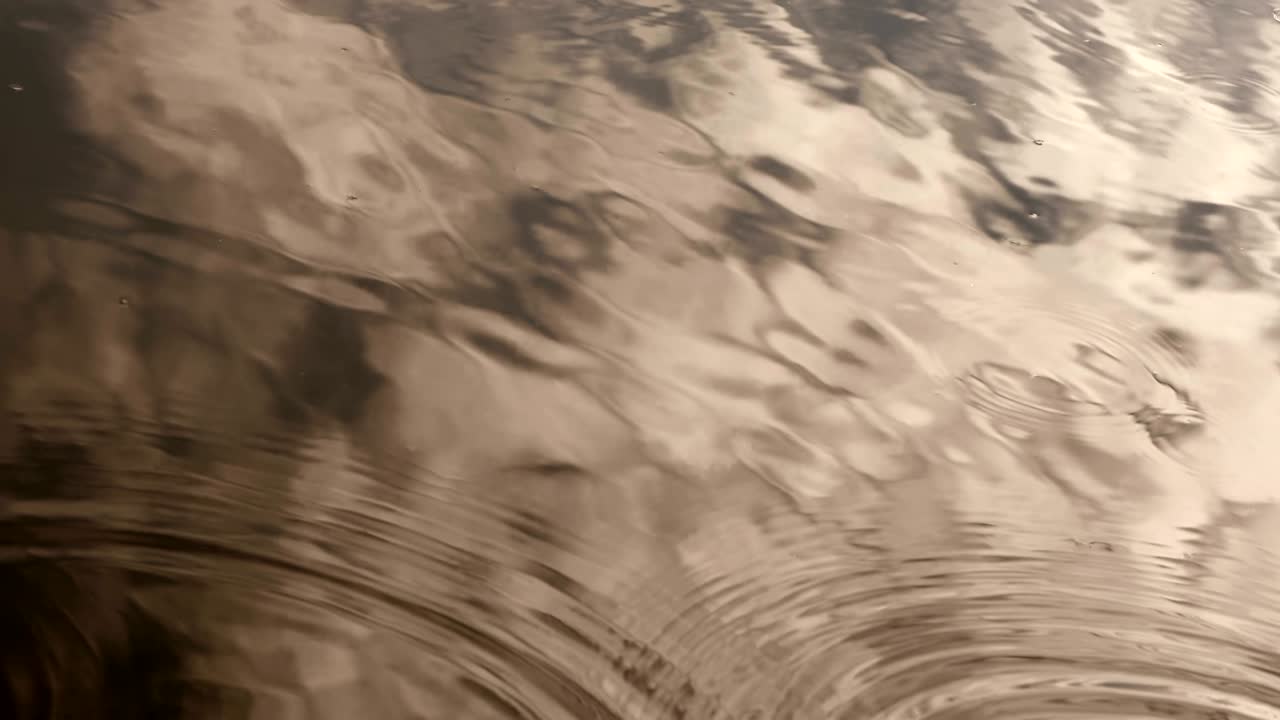 은 황금색 톤은 비가 오는 계절에 강 표면에 떨어지는 강물 방울의 근접 사진입니다.