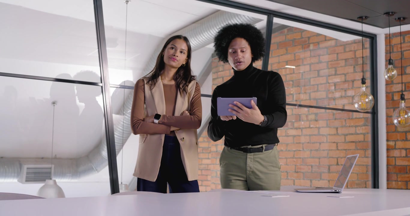 Colleghi che discutono un piano in ufficio, un uomo che tiene un tablet indicando e iniziando il passo successivo vicino al laptop