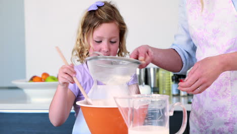 happy mother and daughter making a cake together