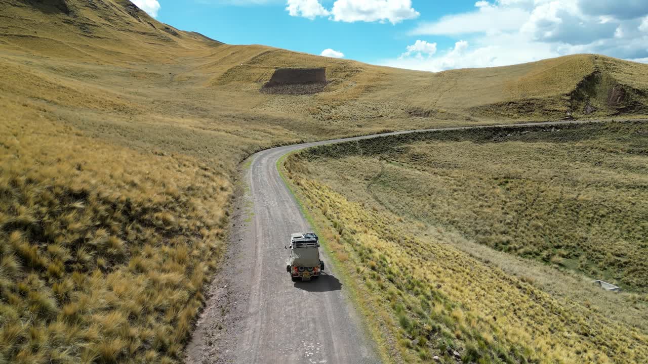 4K cinematic clip of a tuk tuk adventuring across rural Peru, tall grass swaying around it under the warm glow of golden hour