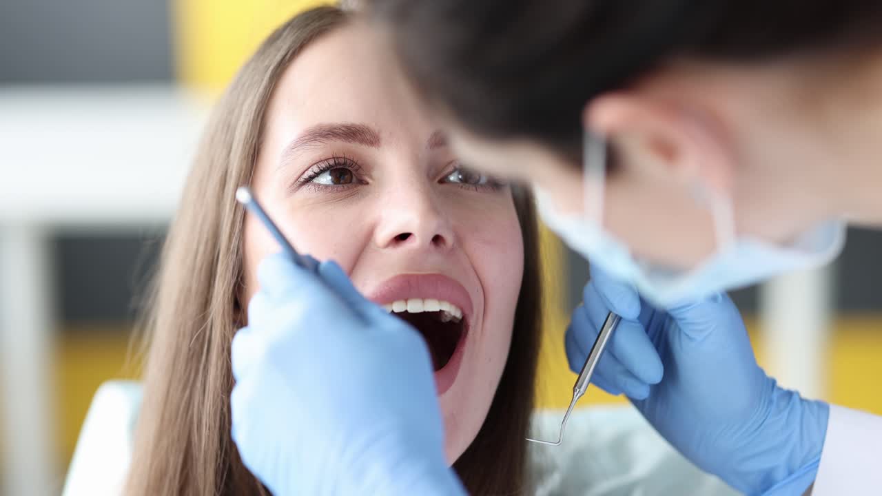 Dentista examinando os dentes de uma jovem paciente - filme 4k