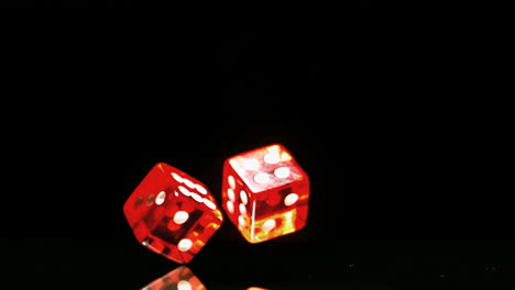 two red dice falling and bouncing close up on black background