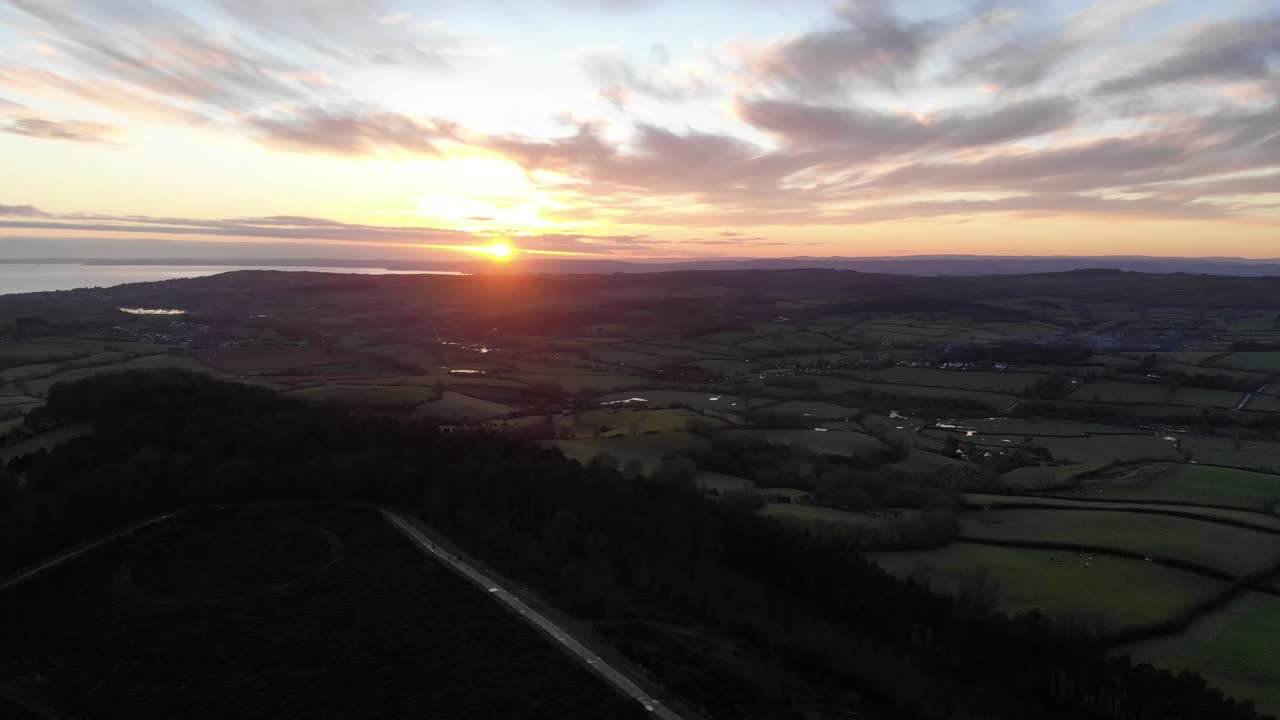 Aerial view of Mutters Moor near Sidmouth, Devon, with the sun setting over the English Channel. Push Forward Shot