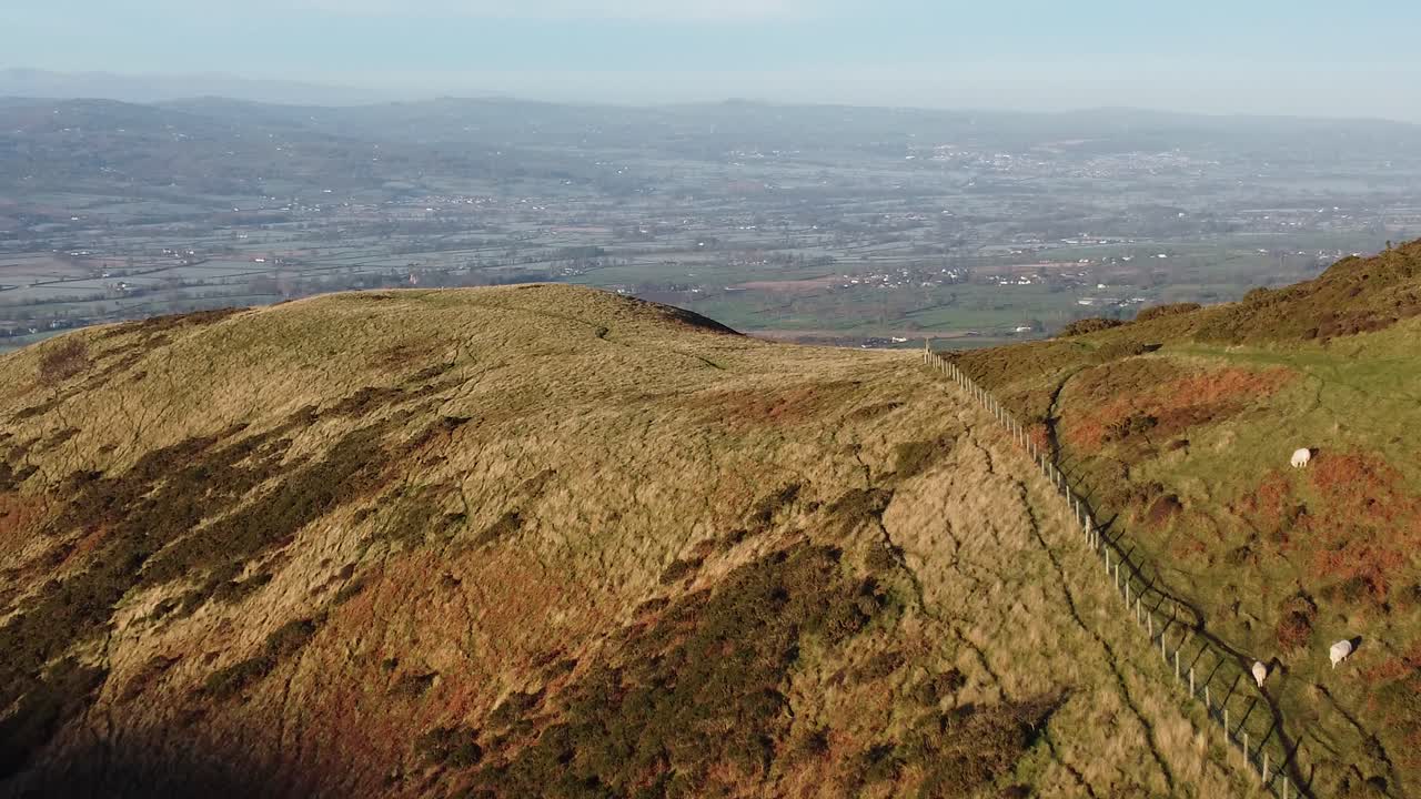 la primera luz del sol en el pico de la montaña de las tierras altas vista aérea a través del vasto paisaje idílico de tierras de cultivo heladas empujar hacia adentro