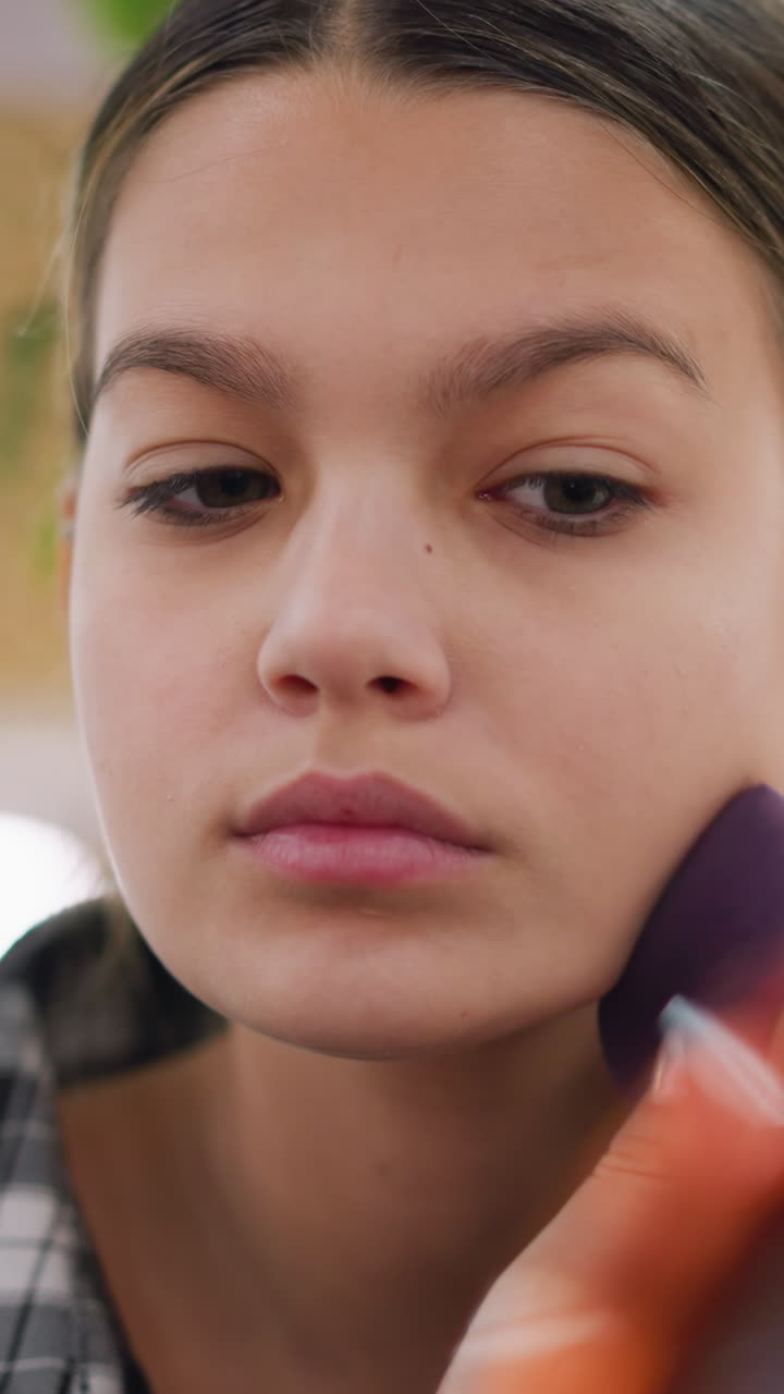 closeup applying sponge under eye with steady hand, methodical concealer blending and mirror check, concentrated expression, warm indoor light and subtle skincare routine demonstration