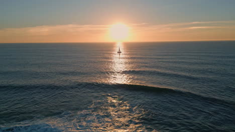silhouette sailing boat sunset aerial view. sun reflecting in beautiful ocean
