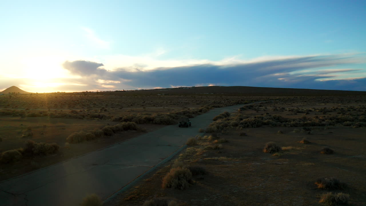 seguimiento aéreo de un vehículo todoterreno en el desierto de mojave durante una puesta de sol dorada