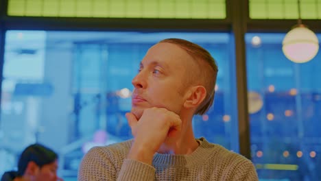 caucasian white male man buy boy model with blue eyes and bright hair is sitting in a cafe, restaurant and waiting, thinking, pondering