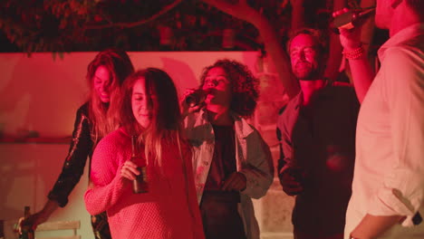 Group-of-friends-standing-in-backyard,-clinking-bottles-of-beer
