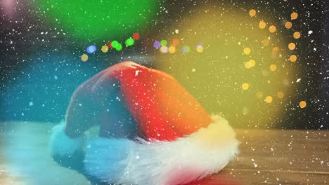 animation of snow falling, santa claus hat, christmas fairy lights flickering over black background