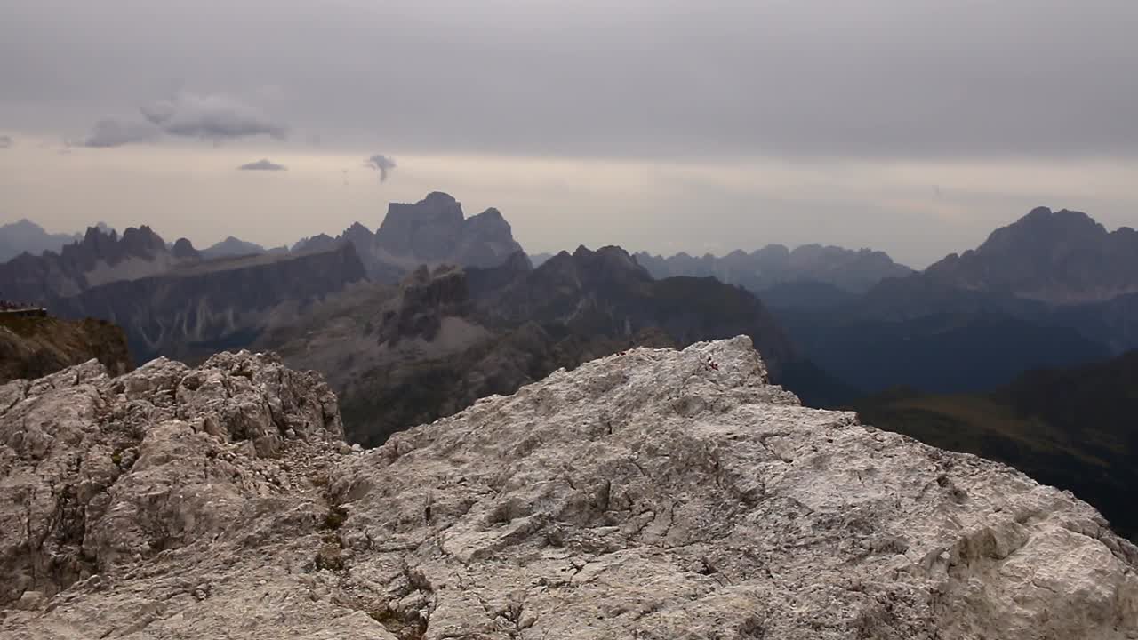 Superficie rocciosa calcarea con spettacolari cime montuose in lontananza sotto un cielo nuvoloso, catturata nella selvaggia catena delle Dolomiti che mostra la bellezza e la consistenza alpina allo stato puro