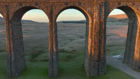 el arco del puente ferroviario atraviesa el páramo estéril de invierno al amanecer.