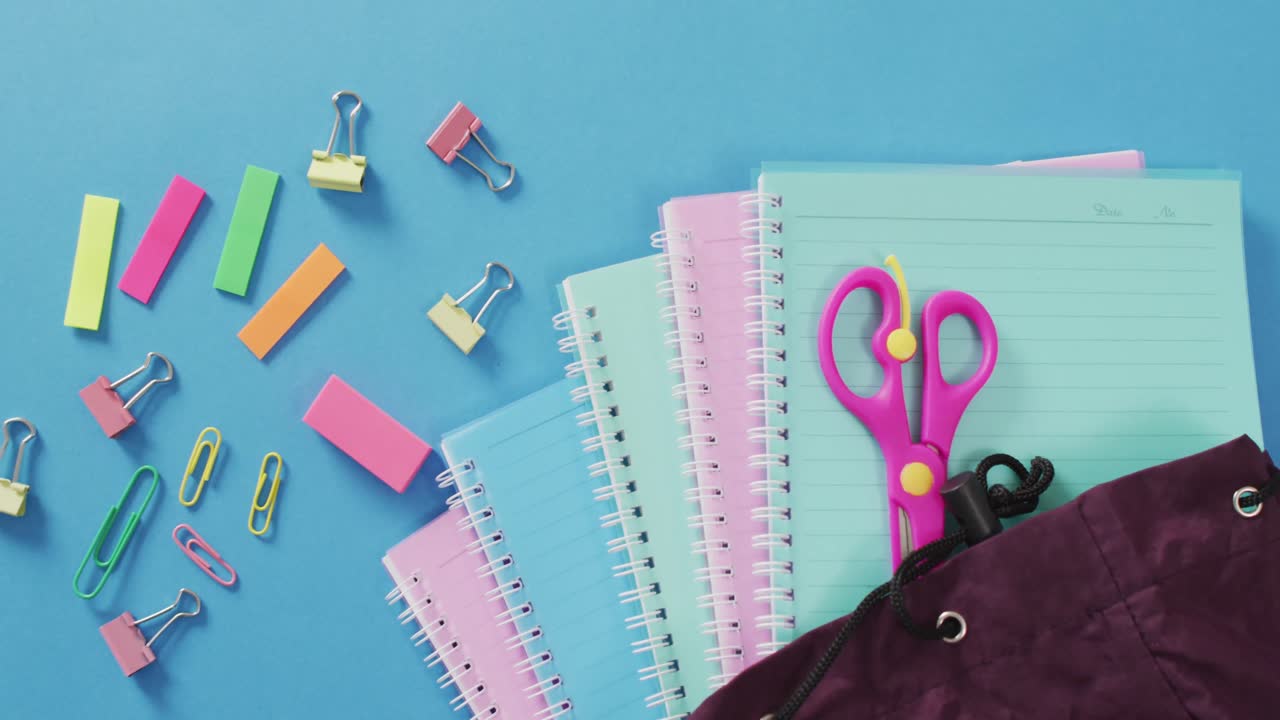 vídeo de útiles escolares, cuadernos, bolígrafos, rotuladores y cuadernos sobre un fondo azul