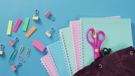 video of school supplies, notebook, pens, marker pen and notebooks over blue background