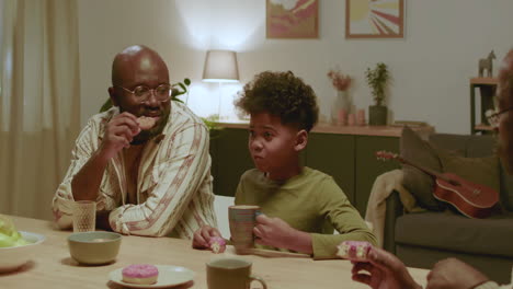 black men and boy eating sweets at home