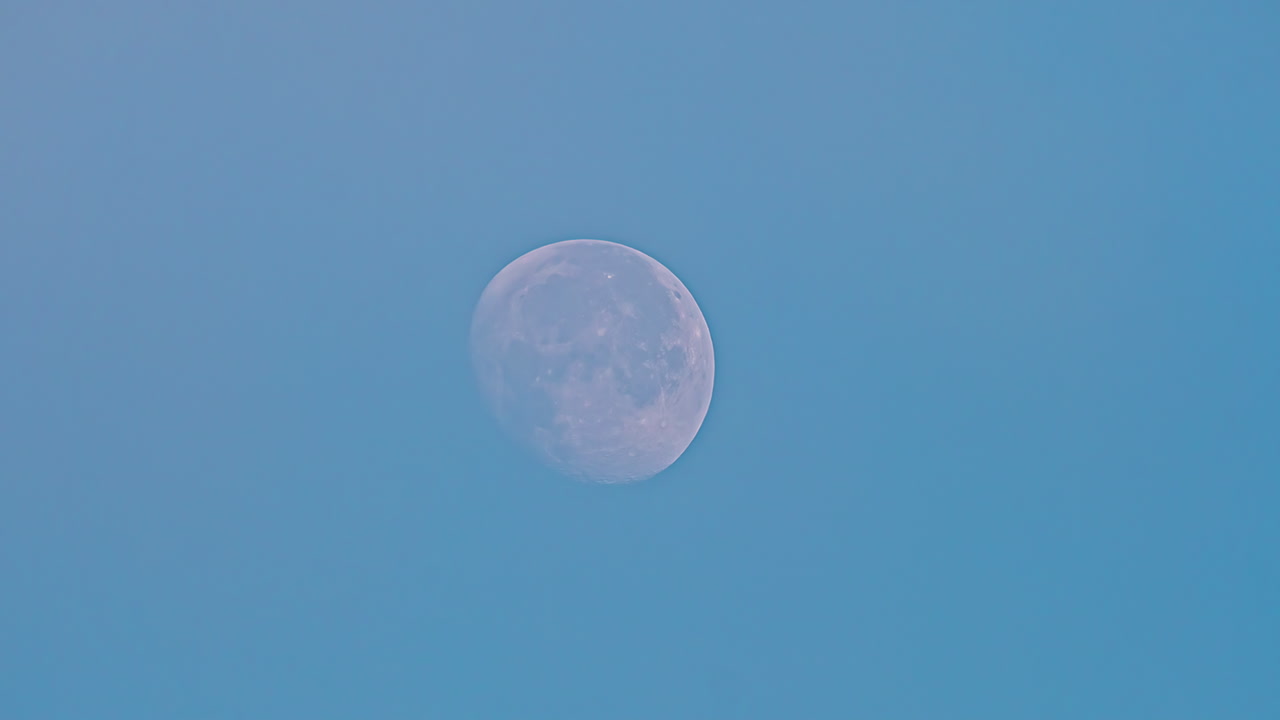 야외에서 푸른 하늘에 떠오르는 하얀 보름달의 저속 줌 샷