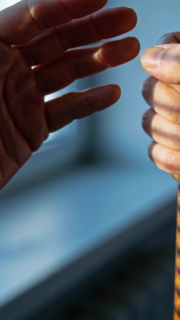Vertical video: Opening left hand reaching toward walking stick at windowsill, assisting grip
