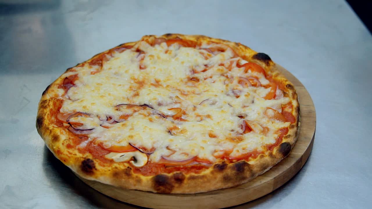 Laying pizza from the oven with spatula on wooden round board. Cooking fresh hot food in the kitchen