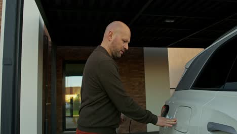 man charging electric vehicle at home