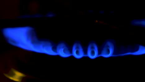 Gas-burning-from-a-kitchen-gas-stove,-dark-background,-cold-winter-and-energy-crisis-concept,-closeup-shot