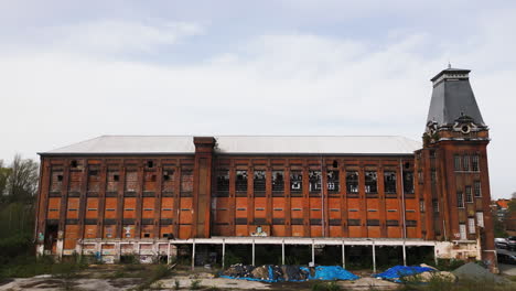 Old-derelict-building-in-Europe,-aerial-ascend-view-with-city-in-background