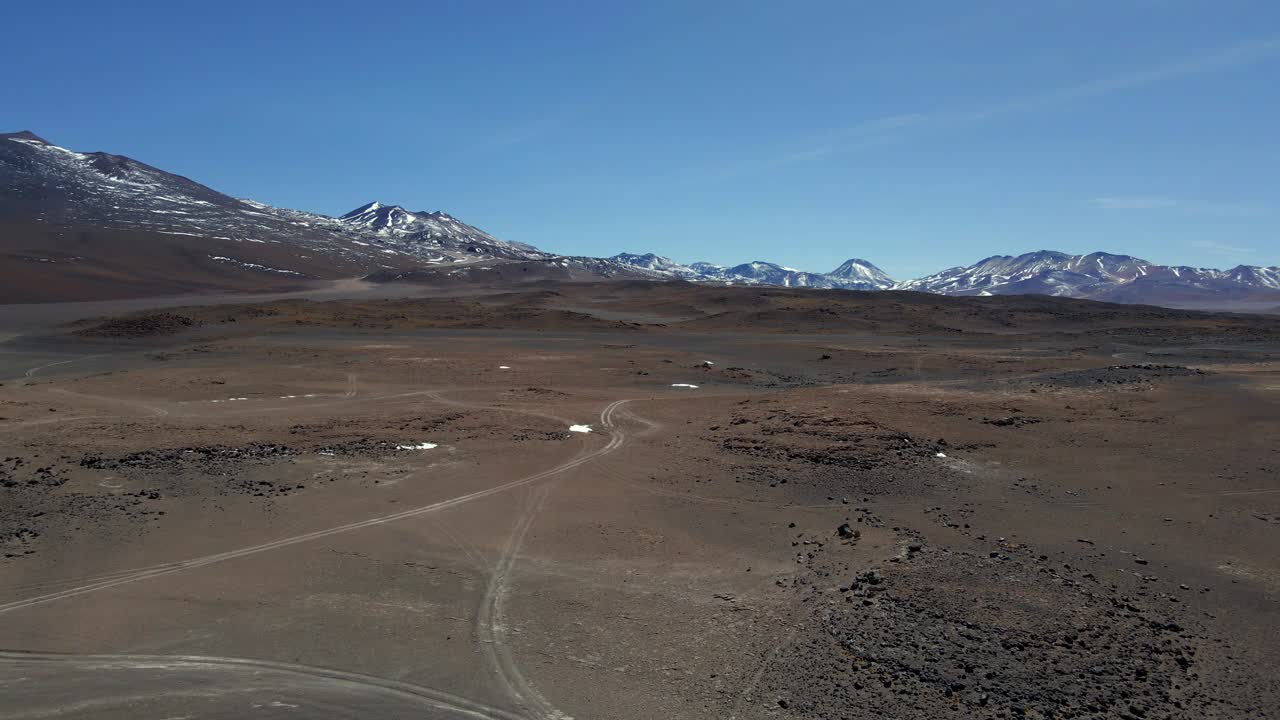 Drone glides across salt flat near Laguna Blanca with lake surface textures and dusty air