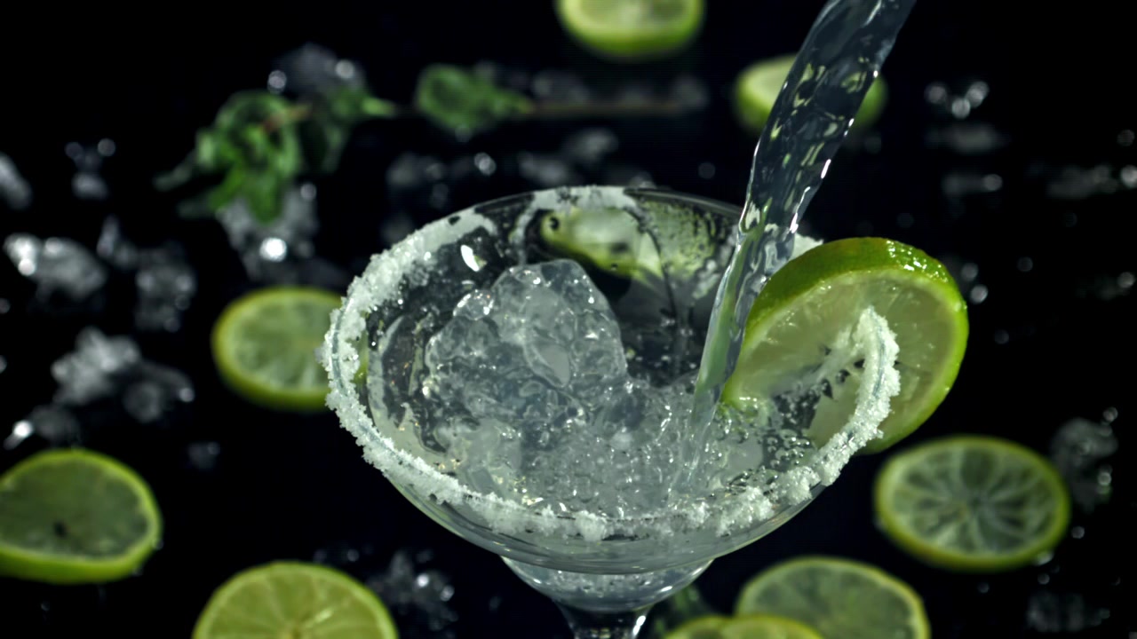Versamento al rallentatore di Margarita in un bicchiere con ghiaccio e lime