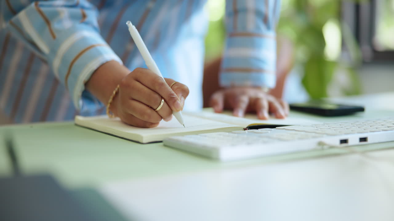 Close Up of Person Writing Notes in a Notebook at a Desk