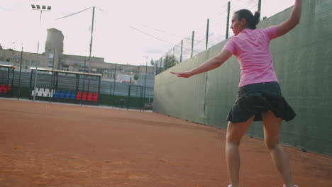 side view of a young caucasian woman playing tennis on a court returning a ball in slow motion