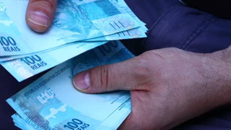 la mujer sostiene y cuenta una gran cantidad de dinero brasileño, los billetes más altos de 100 reales