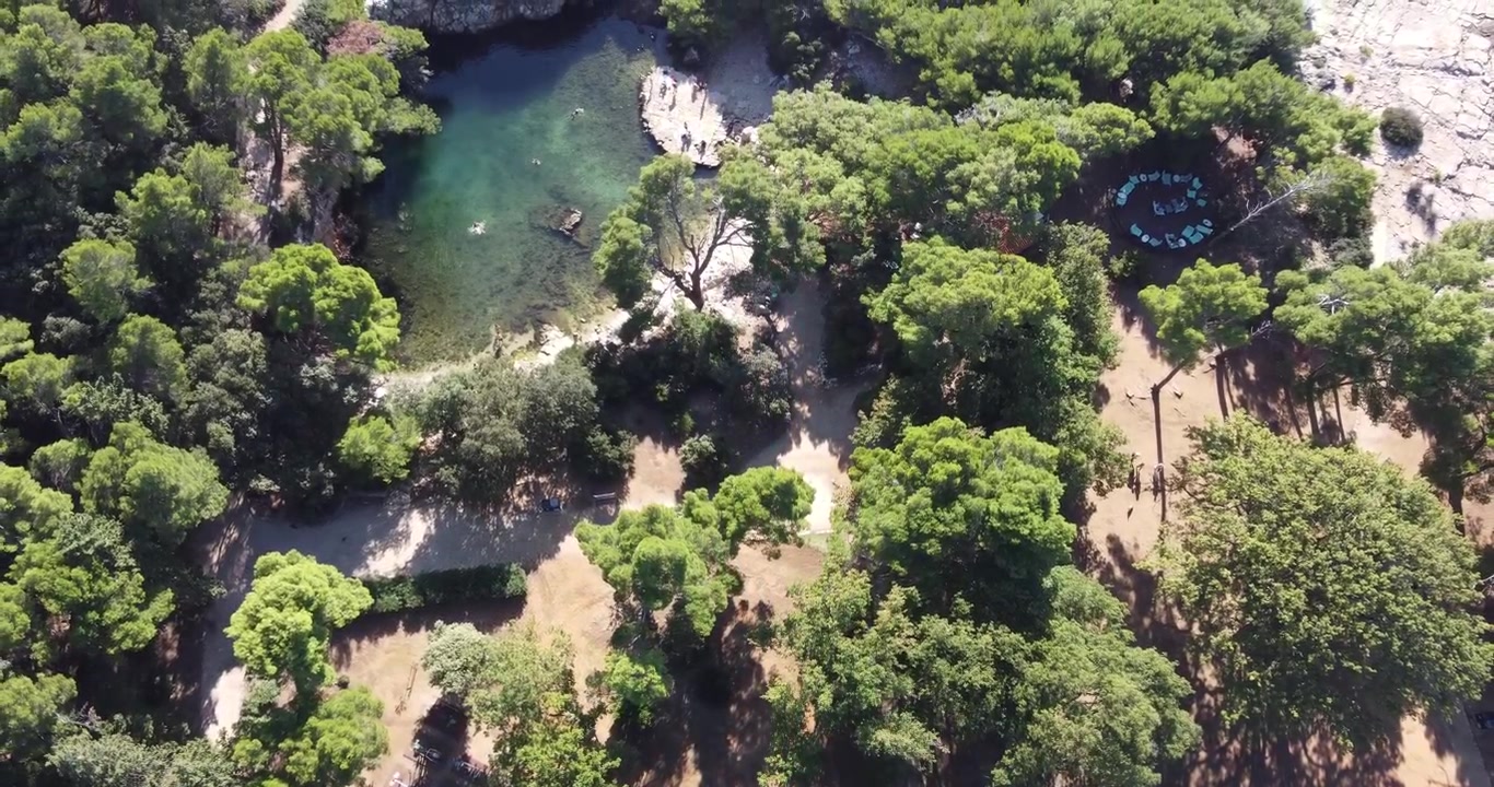Veduta aerea dell'isola di Lokrum, che si allontana verticalmente, mostrando la laguna di acqua salata dove i turisti possono nuotare in una tranquilla giornata estiva di sole; Lokrum, Dubrovnik, Croazia.
