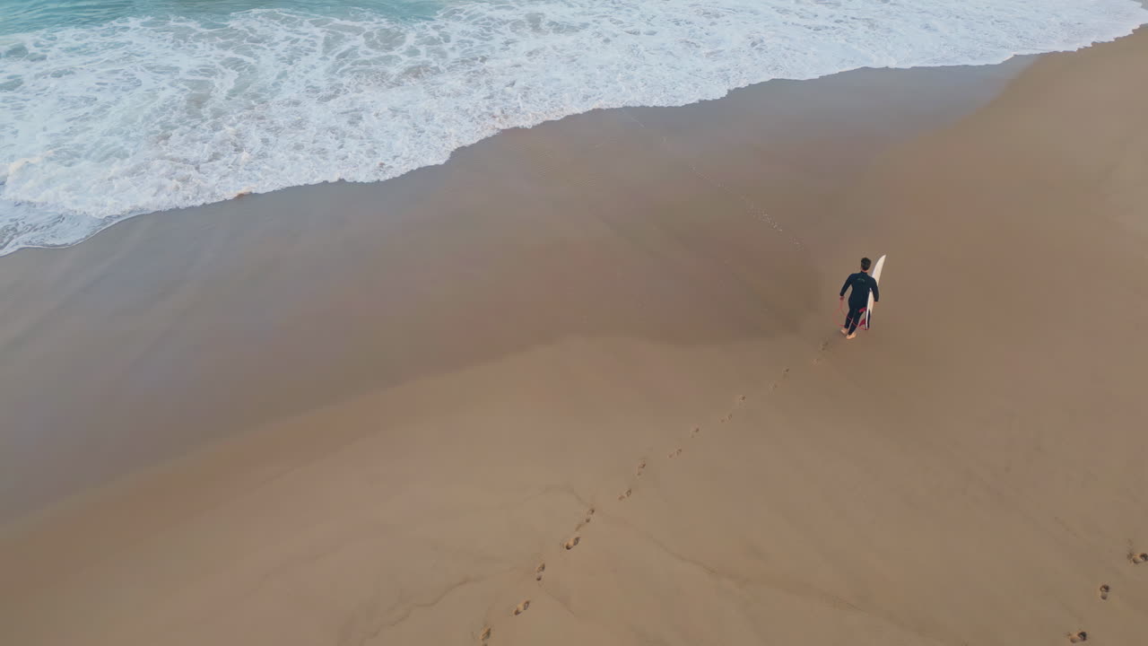 Man surfer leaving footprints walking beach. Drone surfboarder stepping wet sand