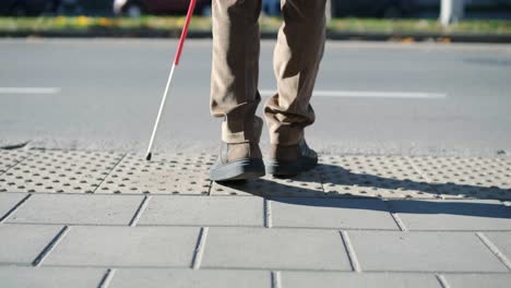 lone blind man detecting tactile tiles, walking to pedestrian crossing safe road