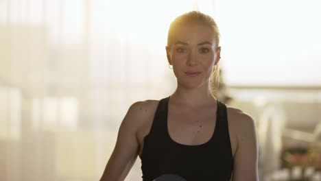 gorgeous woman athlete posing with mat while standing in lens flares on background