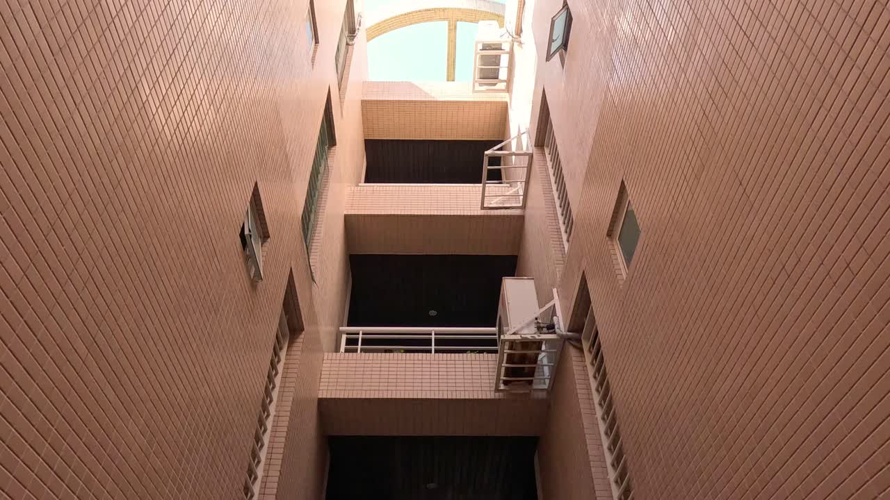 Person climbs stairs in a brick building alleyway