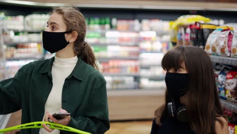 a woman is talking on the phone and at the same time taking juice on the shelf for her daughter